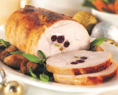 Cooked Roast Turkey sliced on a white plate with condiments